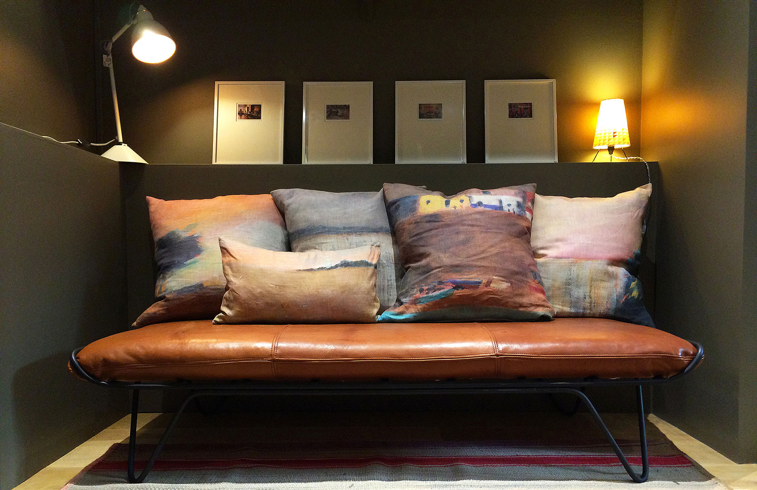 Sur le divan en cuir d'Honoré Déco, des coussins en lin imprimé de maison Lévy éclairés par une lampe Berlingot en tilleul de Sophie Pinard 