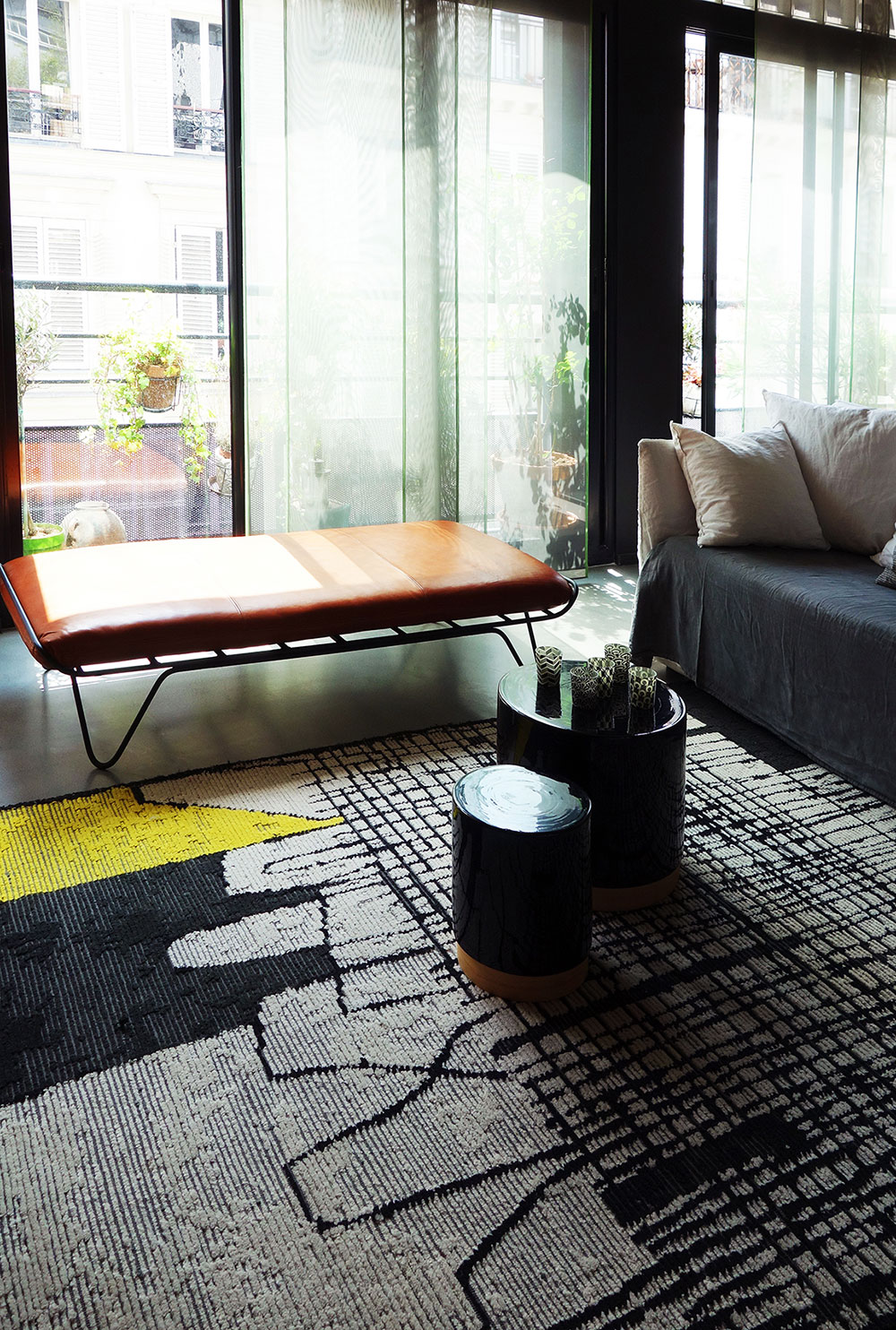 Le pouf en cuir tabac est mis en valeur par le magnifique tapis en laine CC Tapis à motifs jaune et noir