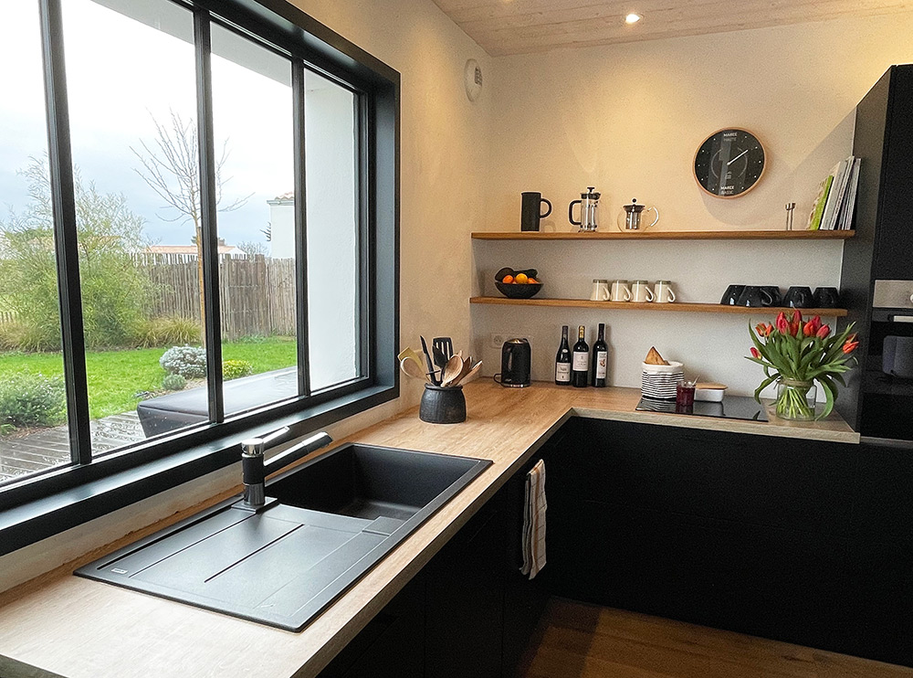 Dans cette maison de Noirmoutier, la cuisine noire était une évidence. Design et fonctionnelle, elle est baignée de lumière par la verrière sur-mesure